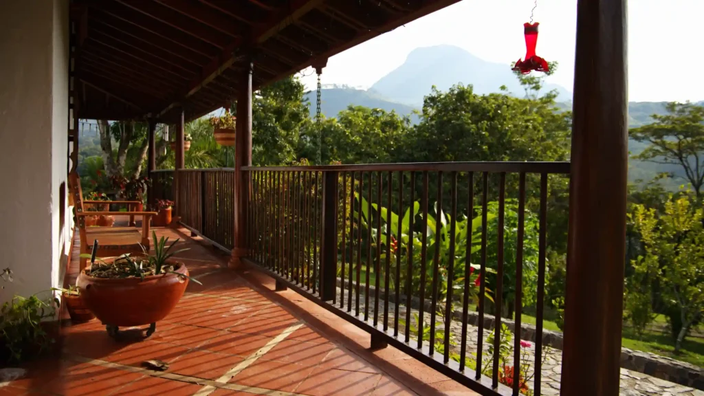 Corredor perimetral de la casa tradicional de la finca La Esperanza en Fredonia rodeado de montañas y vegetación